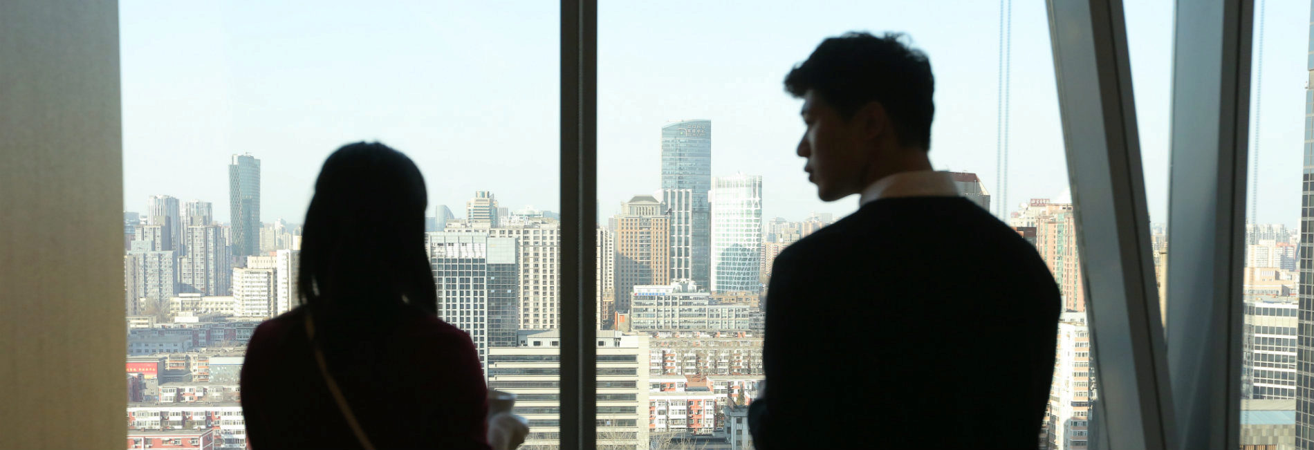 Young man and women looking out at Beijing from Penn Wharton China Center